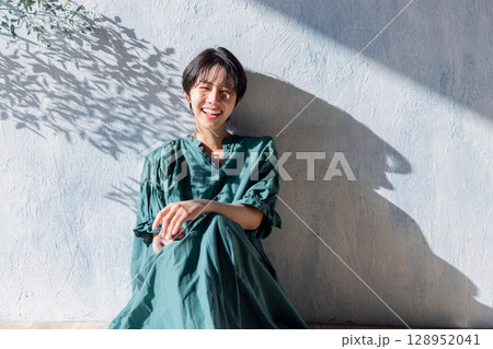 壁に寄りかかるワンピースの女性 128952041