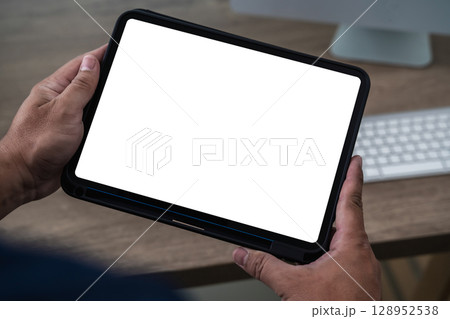 A businessman holds a mockup. iPad digital tablet with blank screen Mockup replaces your design mockup in the office. A businessman holds a mockup. iPad digital tablet with blank screen Mockup replaces your design mockup in the office. 128952538