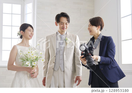 笑顔で会話する新郎新婦とブライダルフォトグラファー 128953180