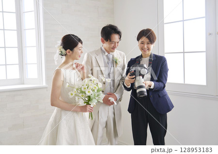 笑顔で会話する新郎新婦とブライダルフォトグラファー 128953183