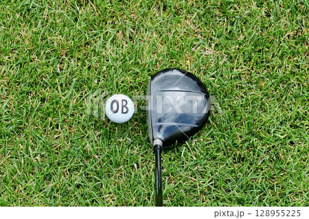 芝生の上に置かれた「OB」文字の入った白いゴルフボールとドライバー 128955225