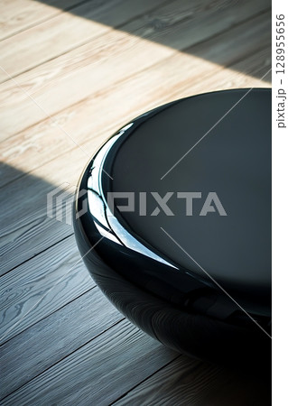 A black round table sits on a wooden floor 128955656