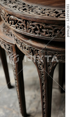 Set of three wooden tables with intricate carvings on the legs 128956381