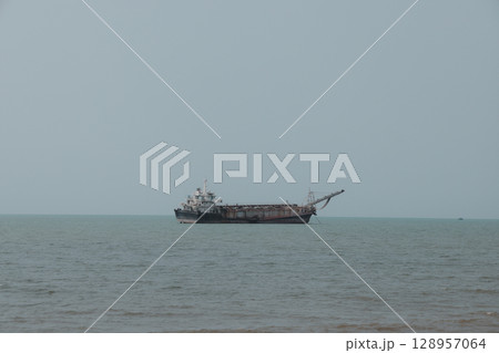 A Cargo Ship is Steadily Navigating Through the Calm and Tranquil Waters of the Ocean 128957064