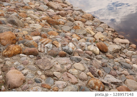 Pebbly Shoreline by Calm Water a picturesque scene that embodies relaxation and tranquility 128957148
