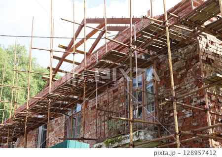 A Construction Site with Scaffolding on a Brick Building shows activity and development A Construction Site with Scaffolding on a Brick Building shows activity and development 128957412