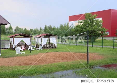 An Outdoor Volleyball Court complete with Cozy Relaxation Cabins and Plenty of Green Space 128957419