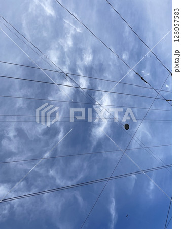 Dramatic Clouds Interwoven with Cables Form an Artistic Contrast Against a Clear Blue Sky Dramatic Clouds Interwoven with Cables Form an Artistic Contrast Against a Clear Blue Sky 128957583