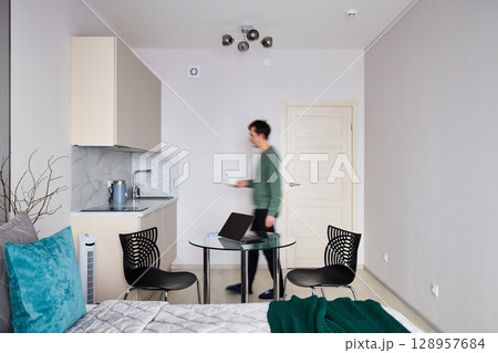 A modern living space with a compact kitchenette and an efficient work setup for comfort A modern living space with a compact kitchenette and an efficient work setup for comfort 128957684