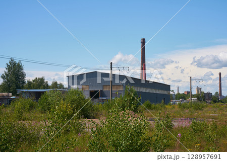 An abandoned factory now stands, surrounded entirely by thriving nature and greenery An abandoned factory now stands, surrounded entirely by thriving nature and greenery 128957691