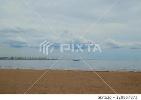 A Serene Beachfront Landscape Featuring Calm Waters and Soft Clouds in the Sky Above 128957873