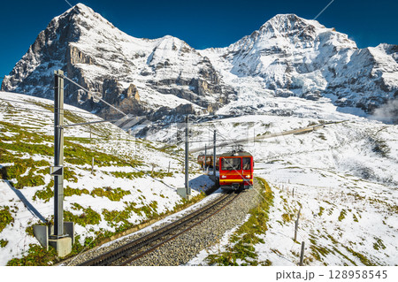 Electric passenger cogwheel train on the snowy slope in Switzerland Electric passenger cogwheel train on the snowy slope in Switzerland 128958545