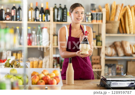 Female salesperson offers to buy bottle of wine in liquor department of grocery supermarket Female salesperson offers to buy bottle of wine in liquor department of grocery supermarket 128959787