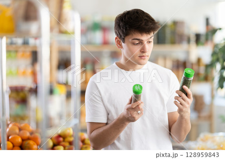Guy shopping at supermarket - choosing spices herbs in grocery supermarket Guy shopping at supermarket - choosing spices herbs in grocery supermarket 128959843
