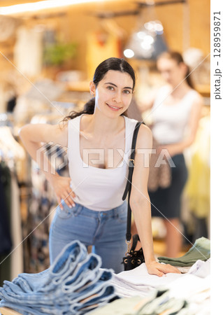 Girl customer chooses denim knee breeches or shorts in store Girl customer chooses denim knee breeches or shorts in store 128959871