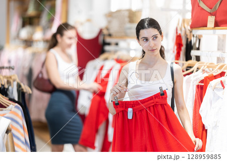 Woman choosing a red skirt in a store Woman choosing a red skirt in a store 128959885