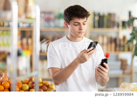 Male buyer checks suitability - scans QR code on jar of soy sauce label in grocery store Male buyer checks suitability - scans QR code on jar of soy sauce label in grocery store 128959984
