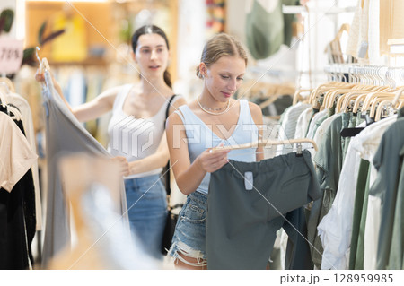 Woman choosing green pants on the background of a friend Woman choosing green pants on the background of a friend 128959985
