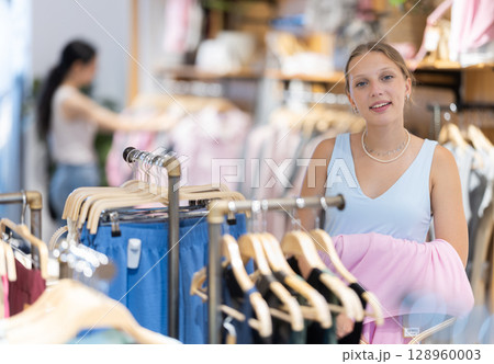 Young woman chooses t-shirt in clothing store 128960003