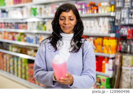 Latin american woman looking for haircare products at cosmetics shop Latin american woman looking for haircare products at cosmetics shop 128960496