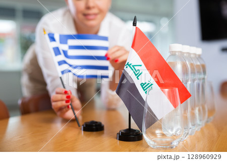 Unrecognizable girl sets midget flags of Iraq and Greece before international negotiations Unrecognizable girl sets midget flags of Iraq and Greece before international negotiations 128960929