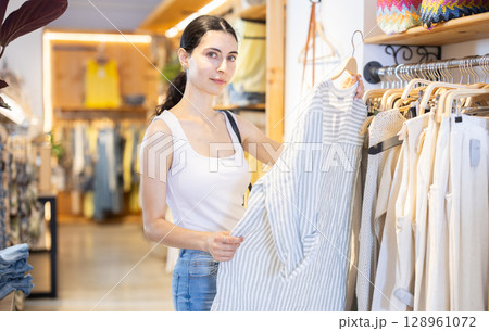 Girl customer chooses blouse in branded store Girl customer chooses blouse in branded store 128961072