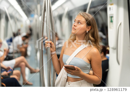 Young woman with phone standing in metro car 128961179