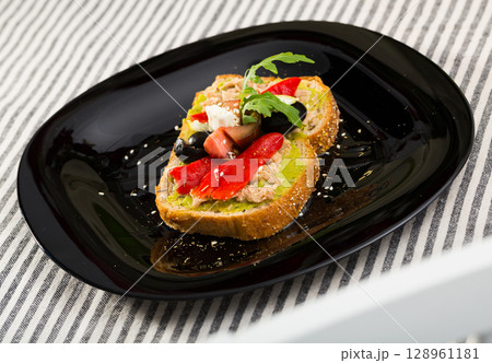 Sandwich with canned tuna, guacamole, olives, arugula and Feta cheese is tasty dish 128961181