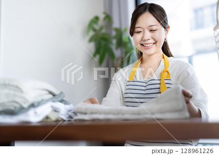 洗濯物をたたむ若い女性 128961226