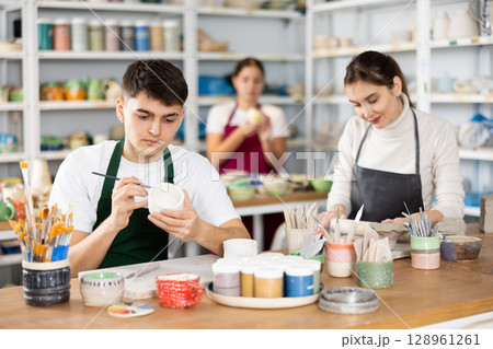 Man painting with brush on handmade clay cup Man painting with brush on handmade clay cup 128961261