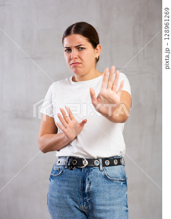 Irritated young woman posing crossly against gray background 128961269