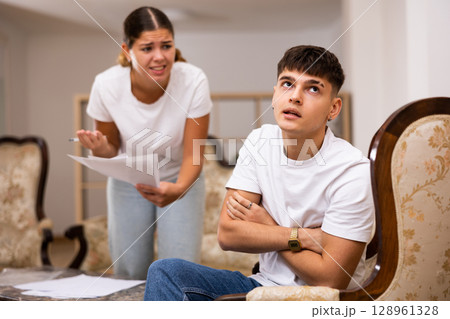 Upset young wife with documents swears at her husband 128961328