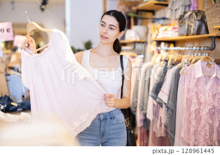 Girl customer chooses blouse in branded store Girl customer chooses blouse in branded store 128961445