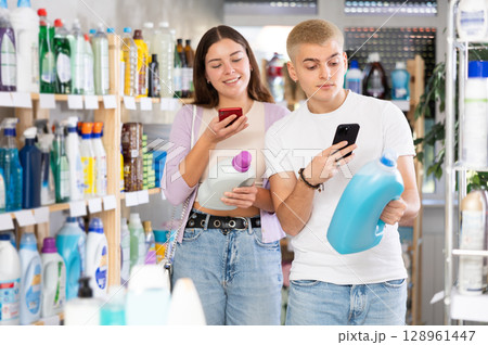 Young couple scanning QR-code on detergent in department store Young couple scanning QR-code on detergent in department store 128961447