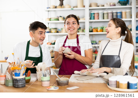 Two young women and young man making pottery 128961561