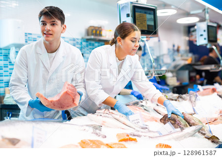 Positive salesman demonstrating tuna in fish store Positive salesman demonstrating tuna in fish store 128961587