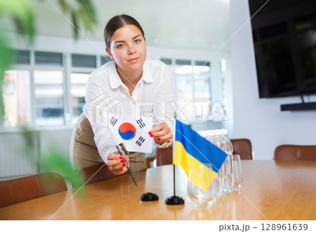 Young lady sets miniatures flags of Ukraine and South Korea for international negotiations Young lady sets miniatures flags of Ukraine and South Korea for international negotiations 128961639