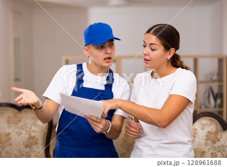 Master discusses with the young landlady of the apartment the plan of repair work Master discusses with the young landlady of the apartment the plan of repair work 128961688