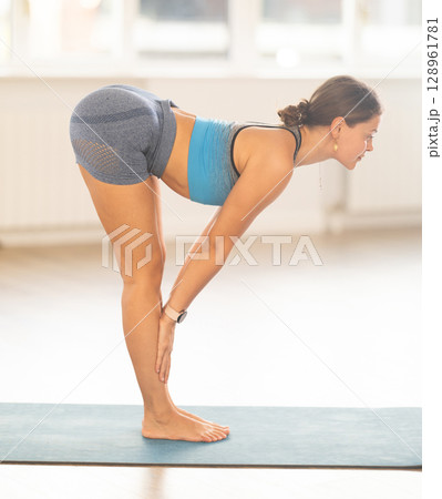 Lover of active lifestyle on yoga mat perform doing ardha uttanasana in gym 128961781