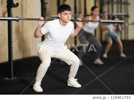 Young guy doing exercises with a barbell in gym 128961783