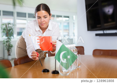 Positive young woman putting little flag of Bahrain on table next to the flag of Pakistan 128961808