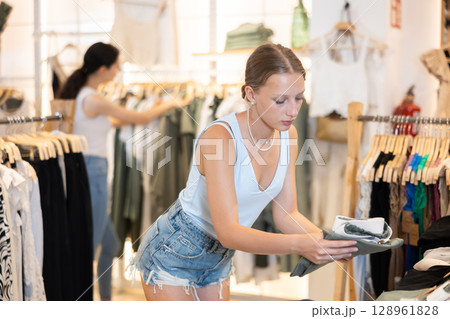 Young woman choosing green pants in store 128961828