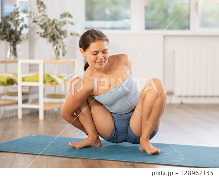 Young woman practicing yoga in kagasana pose Young woman practicing yoga in kagasana pose 128962135