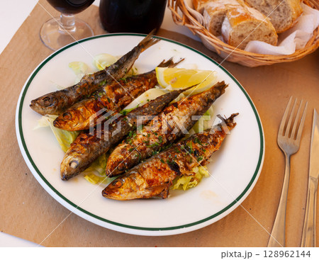 Deliciously fried many sardines served with lemon at plate 128962144