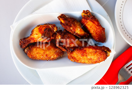 Fried chicken wings with golden crust served with on plate Fried chicken wings with golden crust served with on plate 128962325