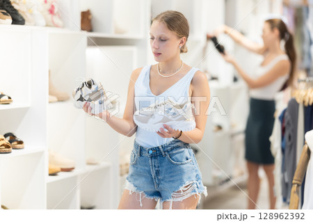 Young woman choosing sneakers in the store Young woman choosing sneakers in the store 128962392