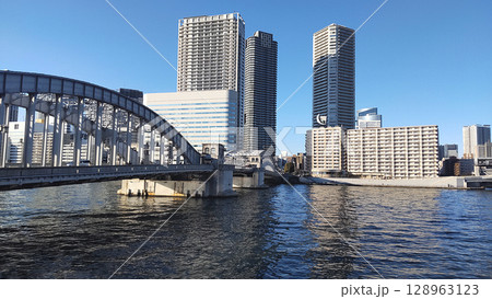 大都会の川沿いから眺めるタワーマンション群と橋のある風景(都会のアーバンライフのイメージ写真) 128963123