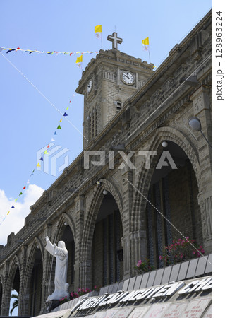 Statue of Jesus Christ in the Catholic cathedral and the clock tower with a cross 128963224