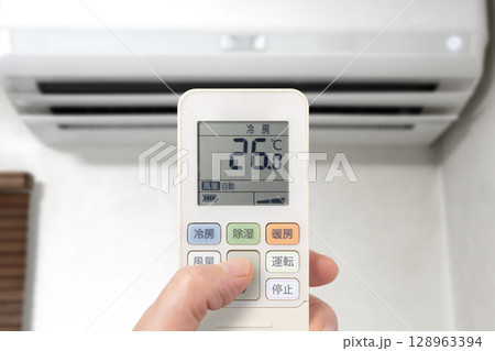 エアコンのリモコンを操作している人 エアコンのリモコンを操作している人 128963394