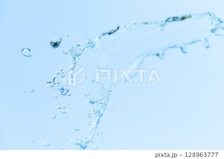 青空をバックに広がる水しぶき 流形を描く透明な水のしずく 128963777